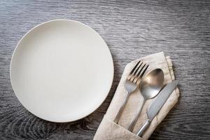 assiette ou plat vide avec couteau, fourchette et cuillère sur fond de carreaux de bois photo