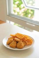 pépites de poulet frit avec pommes de terre frites sur plaque photo