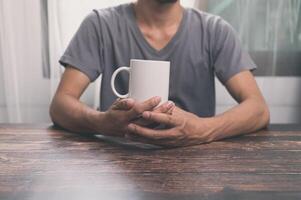 homme tenant un verre d'eau, une tasse de café, sur un bureau, dans son bureau. photo