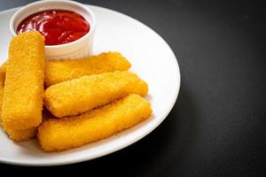 bâtonnets de poisson frits croustillants avec de la chapelure servis sur une assiette avec du ketchup photo