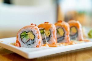 rouleau de saumon sushi avec sauce sur le dessus - style de cuisine japonaise
