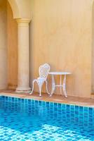 chaise et table blanches vides du côté de la piscine photo