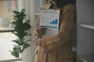 femme d'affaires asiatique utilisant un ordinateur portable et travaillant au bureau avec un document de calculatrice sur le bureau, faisant la planification en analysant le rapport financier, l'investissement dans le plan d'affaires, le concept d'analyse financière. photo