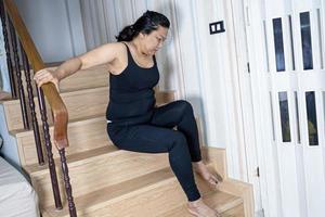 Une patiente asiatique d'âge moyen tombe dans les escaliers à cause de surfaces glissantes photo
