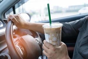 dame asiatique tenant un café glacé dans une voiture dangereuse et risque un accident.