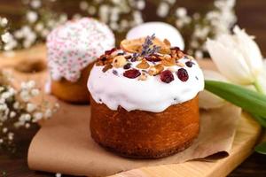 gâteaux de fête avec glaçage blanc, noix et raisins secs avec œufs de pâques sur la table de fête photo