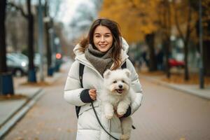 fille dans une blanc veste en marchant vers le bas le rue avec une chien dans sa bras photo