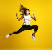 une adolescent fille sauter dans des sports Vêtements sur Jaune Contexte photo