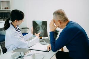 sérieux Asie femelle médecin en utilisant presse-papiers est livrer génial nouvelles parler discuter résultats ou symptômes avec femelle patient dans clinique ou hôpital photo