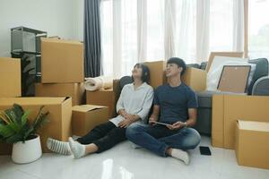 content couple avec papier carton des boites dans Nouveau maison à en mouvement journée. photo