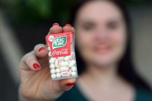 Jeune fille détient TIC Tac difficile bonbons à la menthe pack avec Coca Cola goût. tic tac est une marque de petit difficile menthes, produit par Ferrero photo