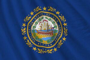 drapeau de l'état américain du new hampshire avec de grands plis agitant de près sous la lumière du studio à l'intérieur. les symboles et couleurs officiels de la bannière photo