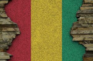 Guinée drapeau représenté dans peindre couleurs sur vieux pierre mur fermer. texturé bannière sur Roche mur Contexte photo