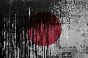 Japon drapeau représenté dans peindre couleurs sur vieux et sale pétrole baril mur fermer. texturé bannière sur rugueux Contexte photo