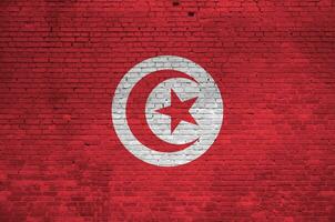 Tunisie drapeau représenté dans peindre couleurs sur vieux brique mur. texturé bannière sur gros brique mur maçonnerie Contexte photo