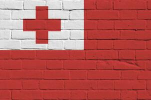 Tonga drapeau représenté dans peindre couleurs sur vieux brique mur. texturé bannière sur gros brique mur maçonnerie Contexte photo