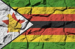 Zimbabwe drapeau représenté dans peindre couleurs sur vieux pierre mur fermer. texturé bannière sur Roche mur Contexte photo