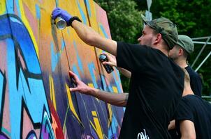 kharkov, ukraine - 27 mai 2017 festival des arts de la rue. de jeunes gars dessinent des graffitis sur des murs en bois portables au centre de la ville. le processus de peinture sur les murs avec des bombes aérosols photo