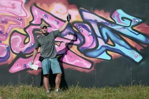 Jeune caucasien Masculin graffiti artiste dessin gros rue art La peinture dans bleu et rose tons photo