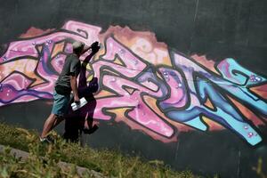 Jeune caucasien Masculin graffiti artiste dessin gros rue art La peinture dans bleu et rose tons photo