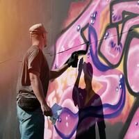 Jeune caucasien Masculin graffiti artiste dessin gros rue art La peinture dans bleu et rose tons photo