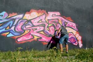 Jeune caucasien Masculin graffiti artiste dessin gros rue art La peinture dans bleu et rose tons photo