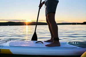 Masculin jambes sur une pagayer planche. photo