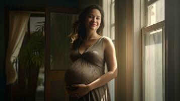 une Enceinte femme se tenait souriant dans le coin de le fenêtre avec lumière diffusion par le la fenêtre. photo