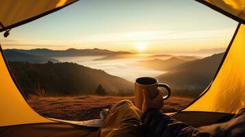 camping en portant une tasse dans un ouvert Jaune tente avec une brumeux Montagne allumé par Naturel lumière. photo