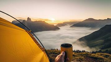 camping en portant une tasse dans un ouvert Jaune tente avec une brumeux Montagne allumé par Naturel lumière. photo