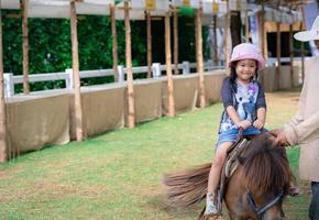 petite fille asiatique apprenant à monter à cheval