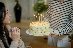 de bonne humeur copains profiter Accueil anniversaire vacances faire la fête. asiatique sœur applaudissement en buvant rouge du vin célébrer avec anniversaire gâteau. photo
