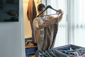 asiatique fille en train de préparer vacances choisir vêtements avec garde-robe dans chambre avant vacances voyage photo