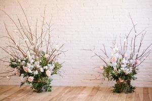 décorations de branches avec de belles fleurs roses et blanches dans le panier sur fond de mur de briques blanches photo