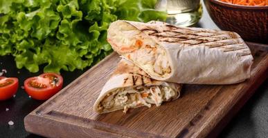 délicieux shawarma frais avec de la viande et des légumes sur une table en béton foncé photo