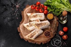 délicieux shawarma frais avec de la viande et des légumes sur une table en béton foncé photo