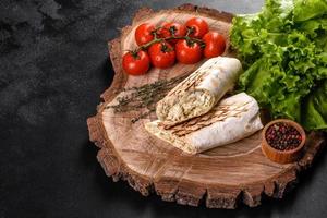 délicieux shawarma frais avec de la viande et des légumes sur une table en béton foncé photo