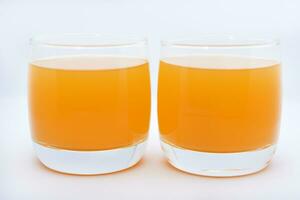 verre des lunettes avec Orange jus sur une blanc Contexte. délicieux Orange refroidissement boire. photo