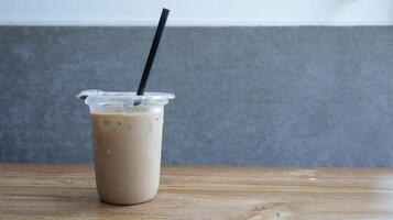 la glace café avec Lait et une paille dans une Plastique tasse à le tableau. non étiquette et copie espace. photo