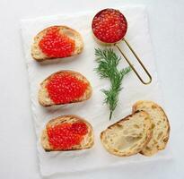 rouge caviar sur tranches de blanc blé pain sur une blanc tableau, concept de luxe et gourmet cuisine, Haut vue photo