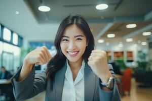 asiatique femme d'affaires montrant une combat pose, magnifique directeur gestes élevage les poings dans moderne bureau, femelle entrepreneur combats une problème, célébrer Succès et réalisation buts photo