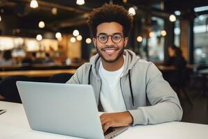 portrait de de bonne humeur noir Masculin étudiant apprentissage en ligne dans café boutique, Jeune africain américain homme études avec portable dans café, Faire devoirs photo