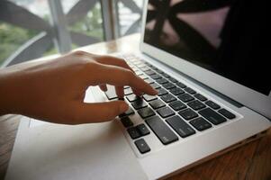 travail par en utilisant une portable ordinateur sur en bois tableau. mains dactylographie sur une clavier. photo