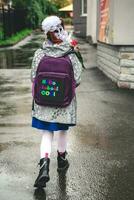 une écolière fille va à école sur septembre 1 avec fleurs et une sac à dos avec le une inscription Bonjour école photo