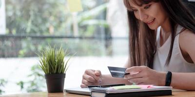 femme souriante utilise un téléphone portable pour faire des achats en ligne avec une carte de crédit