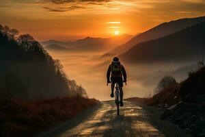 arrière vue de une cycliste équitation une vélo sur une Montagne route contre le coucher du soleil Contexte photo