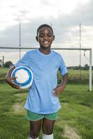 portrait de souriant Jeune Football joueur en portant Balle sur Football sol photo