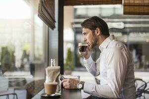 homme d'affaire avec tablette dans une café en buvant café de verre photo