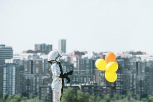 garçon habillé comme un astronaute en portant des ballons dans le ville photo