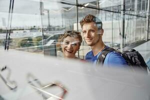 portrait de souriant couple à le aéroport à la recherche en dehors de fenêtre photo